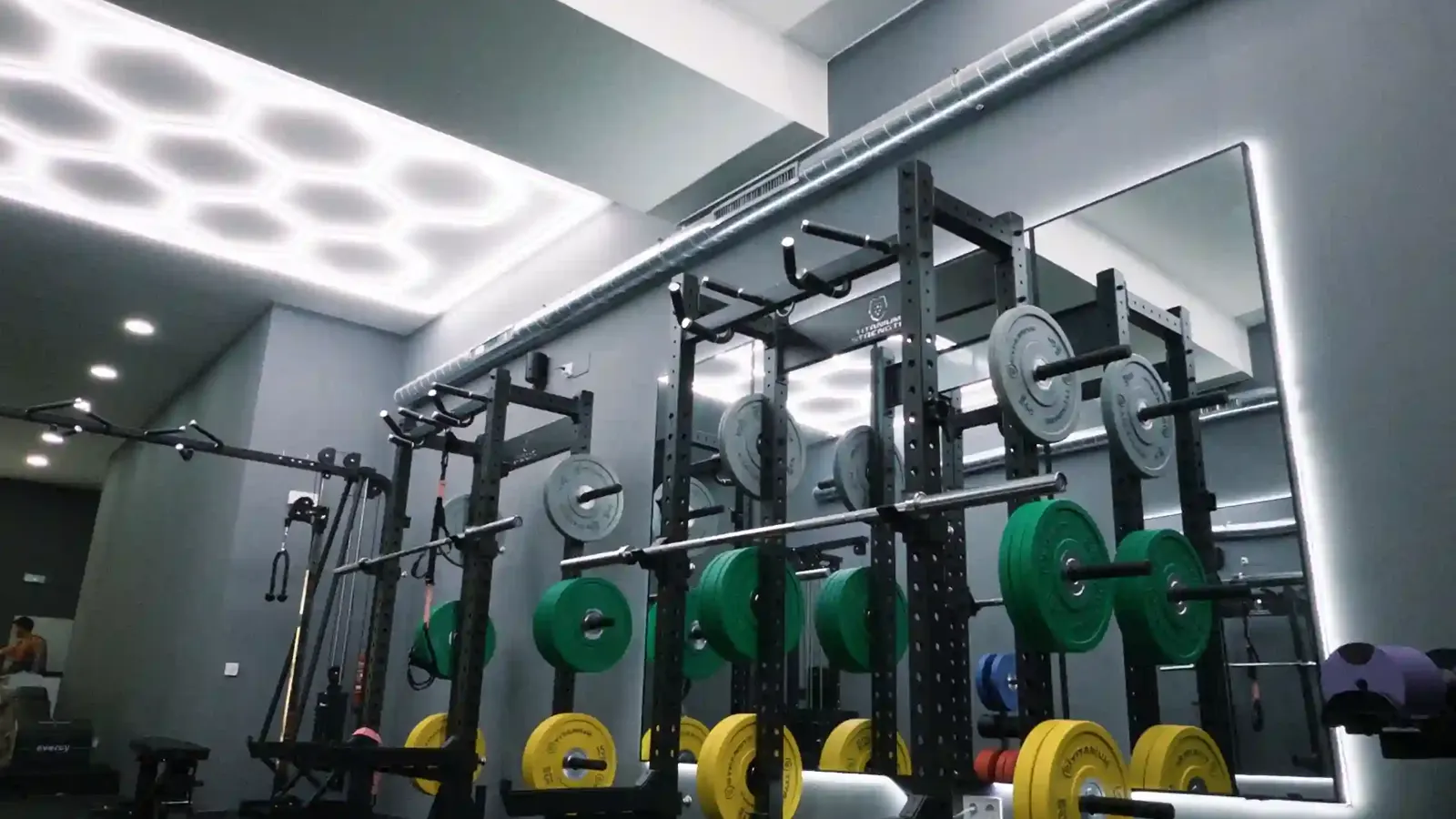 Sala de fuerza de Barcelona Barbell Club en Passeig de Sant Joan, con racks de potencia, discos calibrados y zona de césped funcional